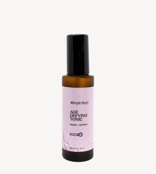 An amber bottle of Simple Body Age Defying Tonic on a tan background