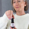 Woman holding a jar of Simple Body Age Defense Serum with a gray background
