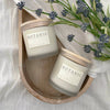 Two Botanic candles on a wooden tray with lavender flowers.