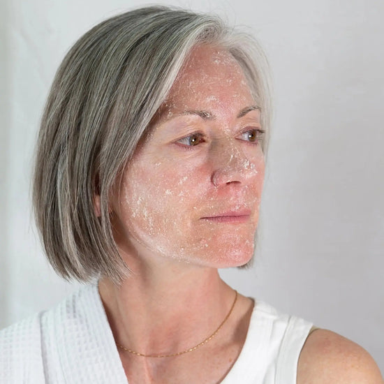 Michelle with Simple Body Bamboo Face Polish on her skin looking sideways wearing a white robe with a white background.