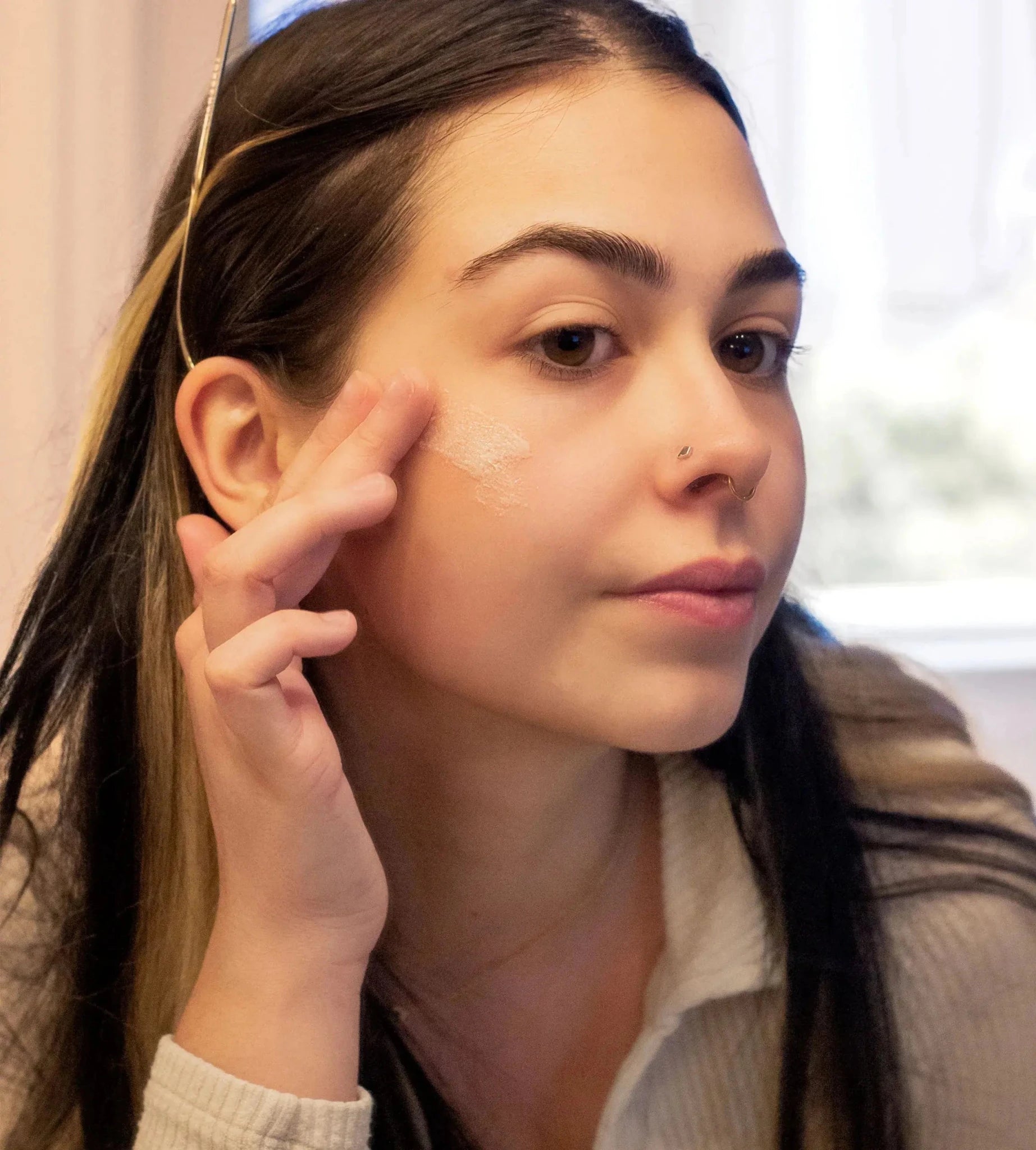 A woman demonstrating the texture of the Simple Body Bamboo Face Polish with long dark hair and dark eyes.