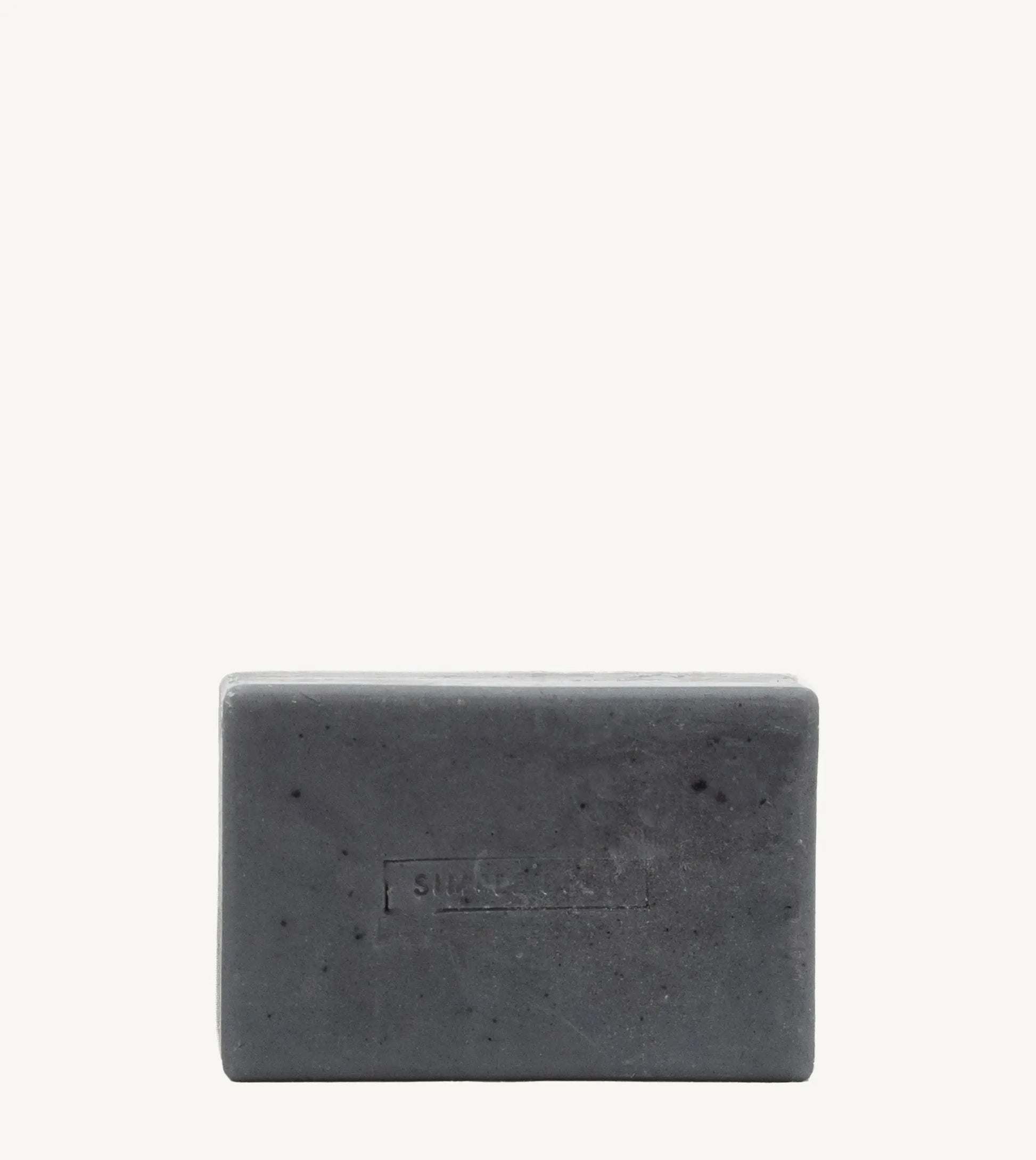 A handmade bar of soap with a gray color and an embossed design on it, placed against a white background.