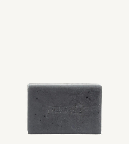 A handmade bar of soap with a gray color and an embossed design on it, placed against a white background.