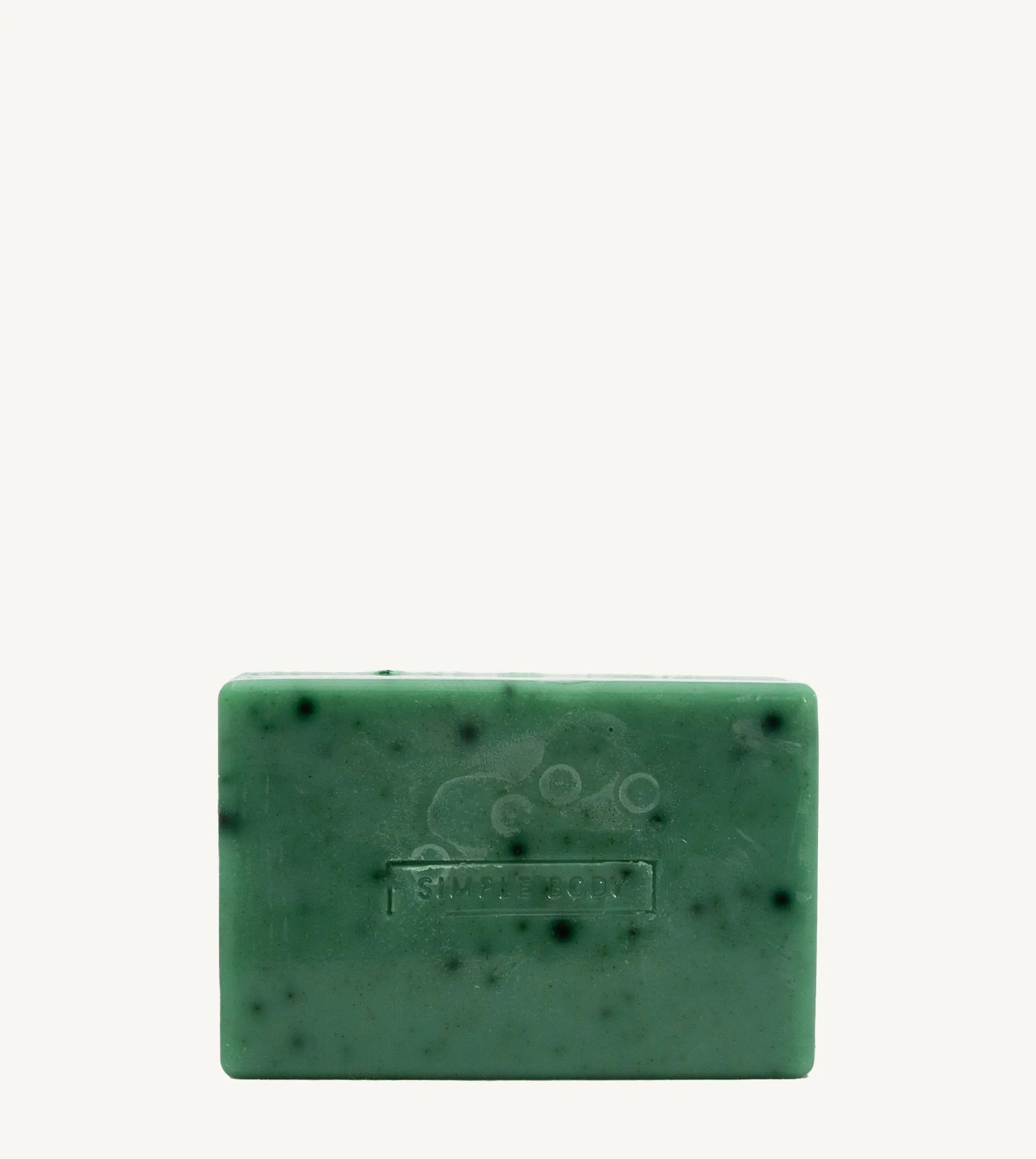 A handmade bar of soap with a green color and an embossed design on it, placed against a tan background.