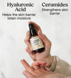 Hand holding a bottle of Simple Body Barrier Defense Serum with text about Hyaluronic Acid and Ceramides on a white background