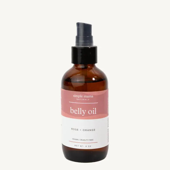 Bottle of Simple Mama belly oil with a pink label on a tan background