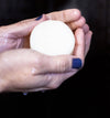 Hand holding a white bar of soap against a black background