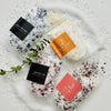 Four bath salts with decorative packaging on a textured surface
