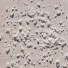 A close-up texture shot of Bloom Bath Co Eucalyptus and Lavender Bath Salt scattered across a light beige surface under bright sunlight.