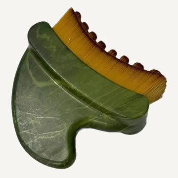 A jade lymphatic massage tool with a green polished jade stone handle and a yellow bristle brush on top, shown on a white background.