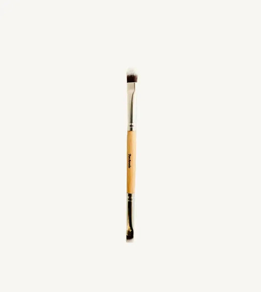 A photo of Pure Anadas vegan Duo Makeup Brush with one side that is a soft, feathery brush and the other an angled brush with a wooden, natural handle on a tan background.