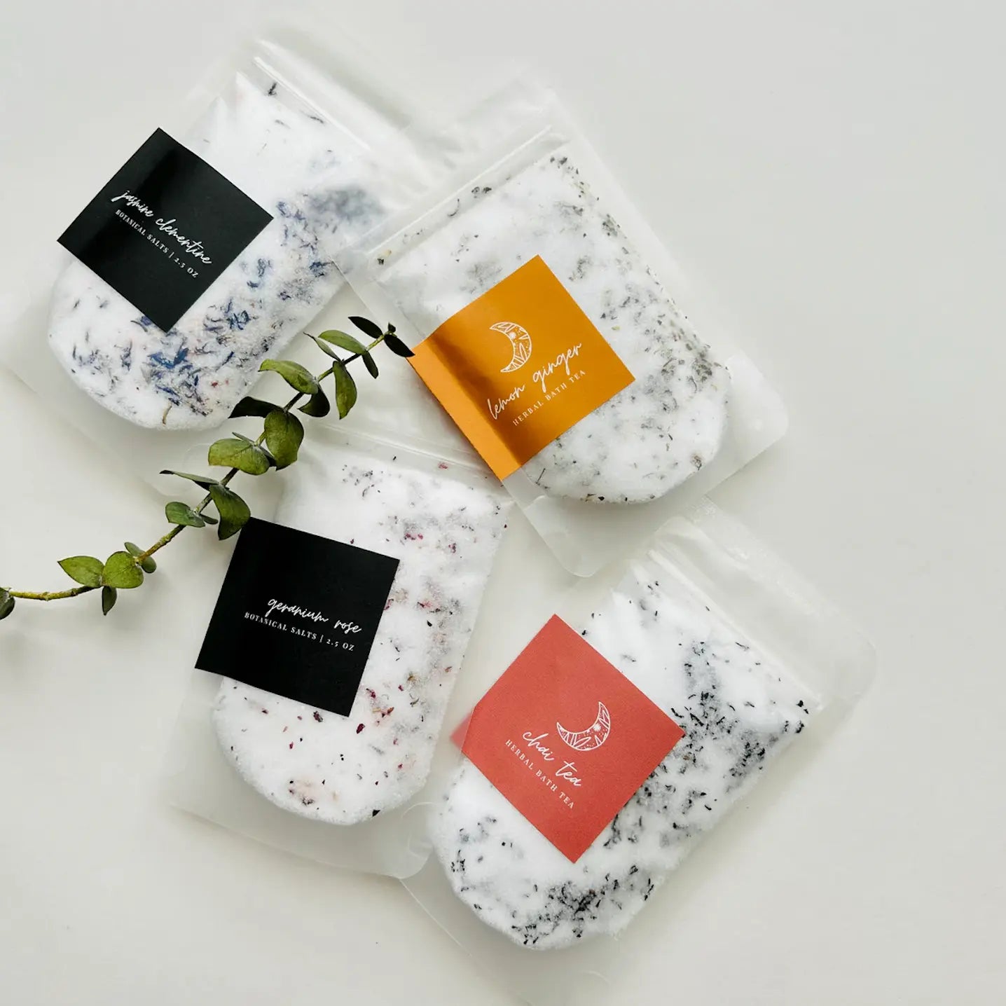 Five packets of bath salts with colorful labels on a white background