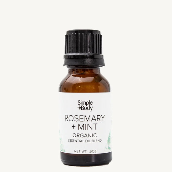 Brown glass bottle of Simple Body Rosemary + Mint organic essential oil blend on a white background