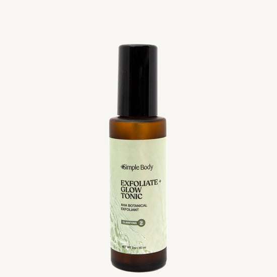 A recyclable glass spray bottle labeled 'Exfoliate + Glow Tonic' by Simple Body, designed for skincare.