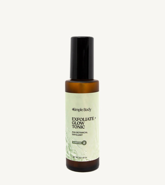 A recyclable glass spray bottle labeled 'Exfoliate + Glow Tonic' by Simple Body, designed for skincare.