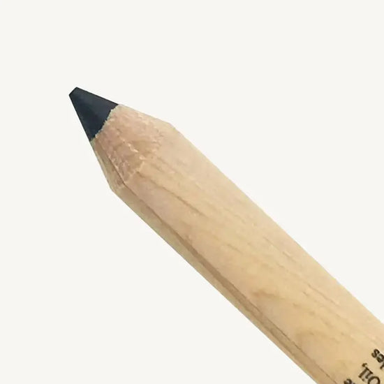 A closeup of Pure Anada's Black Eyeliner Pencil against a tan background.