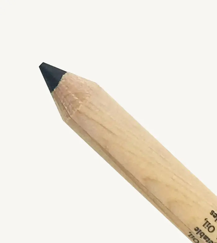 A closeup of Pure Anada's Black Eyeliner Pencil against a tan background.