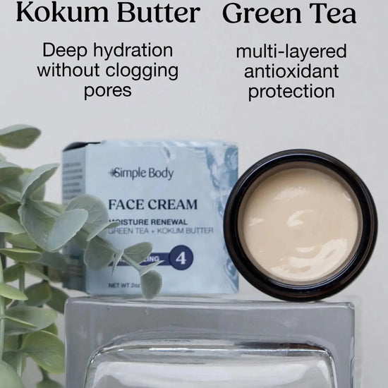 A Jar of open Simple Body Face Cream showing off the creamy white texture and key ingredients Kokum Butter and Green Tea called out as beneficial for the skin with a green plant on the side and white background.