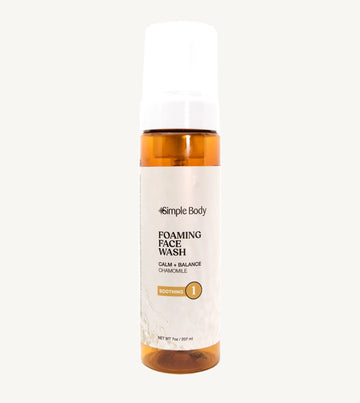 An amber colored bottle of Simple Body Foaming Face Wash in chamomile, designed for sensitive skin.