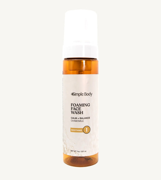 An amber colored bottle of Simple Body Foaming Face Wash in chamomile, designed for sensitive skin.