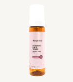 An amber colored pump bottle of Simple Body Foaming Face Wash with pink rose floral water visible inside.