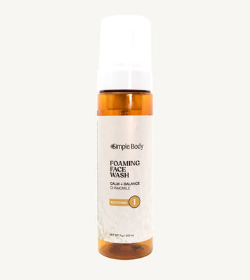 An amber colored bottle of Simple Body Foaming Face Wash in chamomile, designed for sensitive skin.
