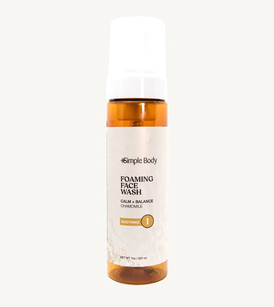 An amber colored bottle of Simple Body Foaming Face Wash in chamomile, designed for sensitive skin.