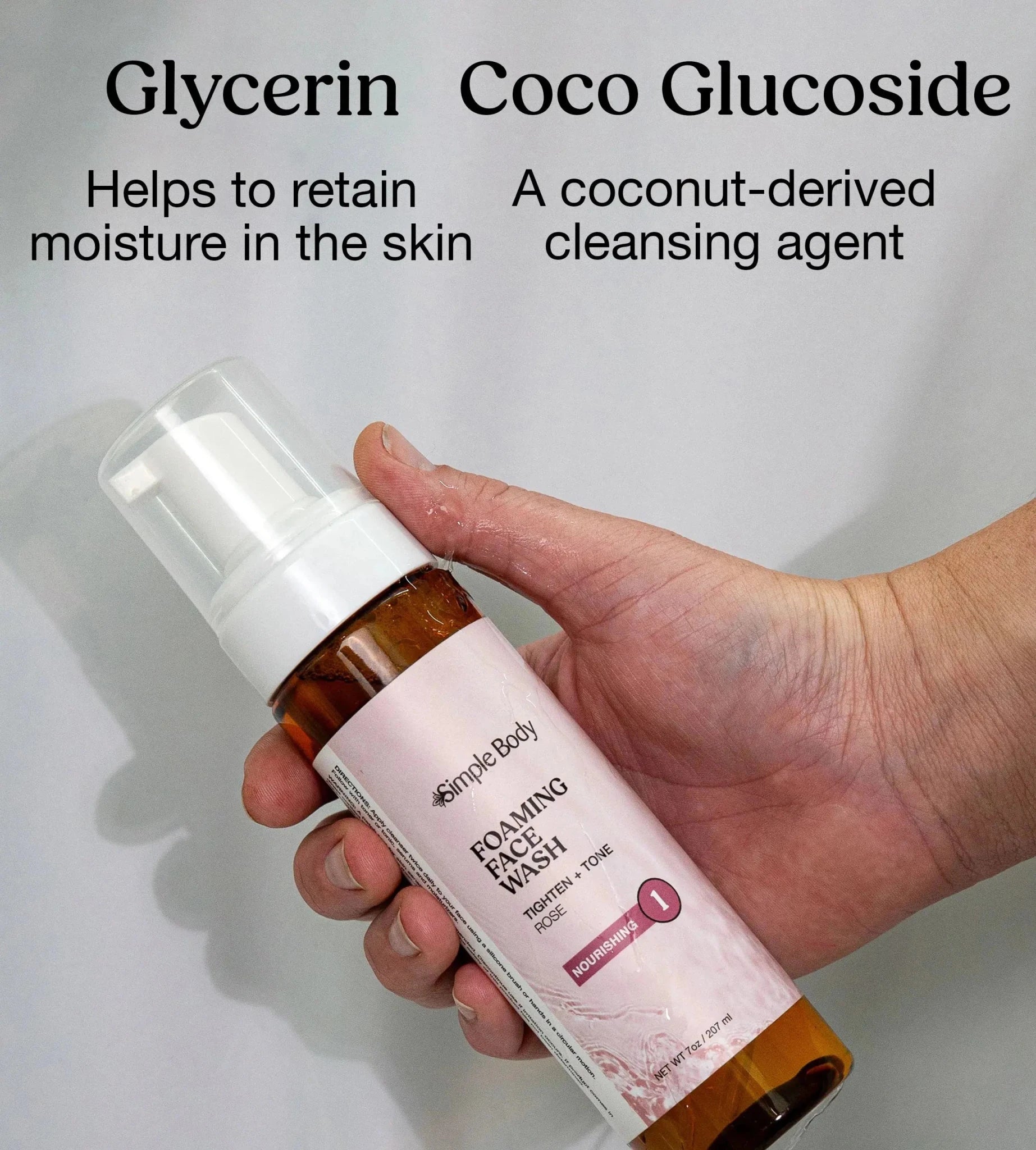 Simple Body Foaming face wash bottle held by a hand with text that explains two key ingredients Glycerin and Coco Glucoside on a green background.