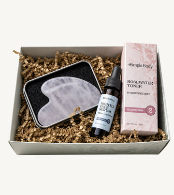 Simple Body Gua Sha gift set including a gua sha tool, Nightly Face Serum, and a Rosewater Toner in a box with crinkled paper