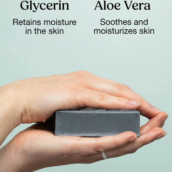 Hands holding a Simple Body Handmade Soap calling out key ingredients including Glycerin that retains moisture in the skin and Aloe Vera that soothes and moisturizes skin on a mint green background.