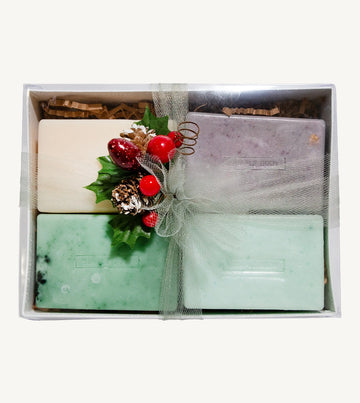 Set of Simple Body handmade soaps including Himalayan Magic Soap, Breathe Better Eucalyptus soap, Lemongrass soap, and Rosemary Mint Soap with decorative elements in a box on a white background