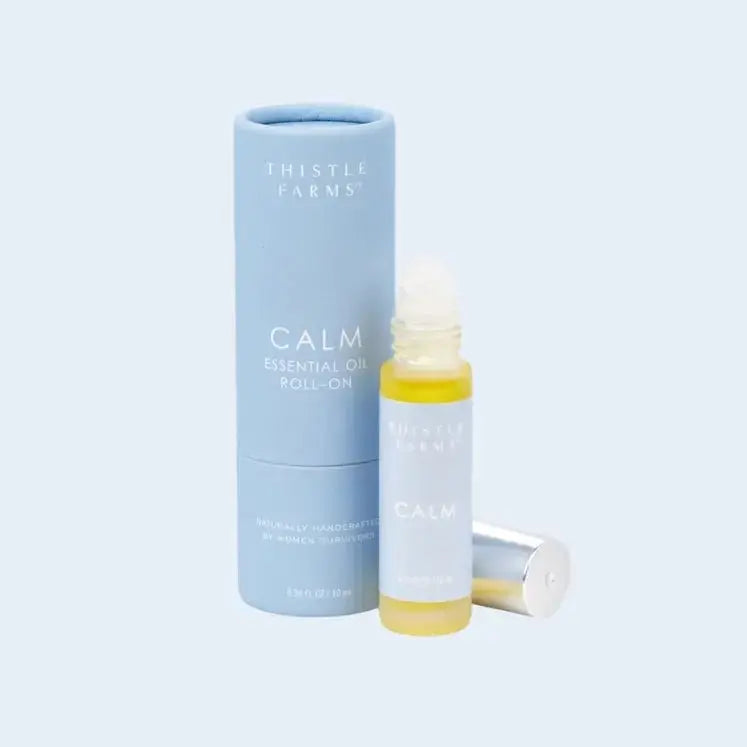 Thistle Farms Calm essential oil roll-on bottle and packaging on a light blue background