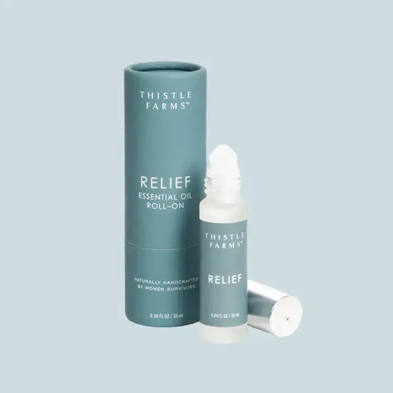 Thistle Farms Relief essential oil roll-on bottle and packaging on a light blue background