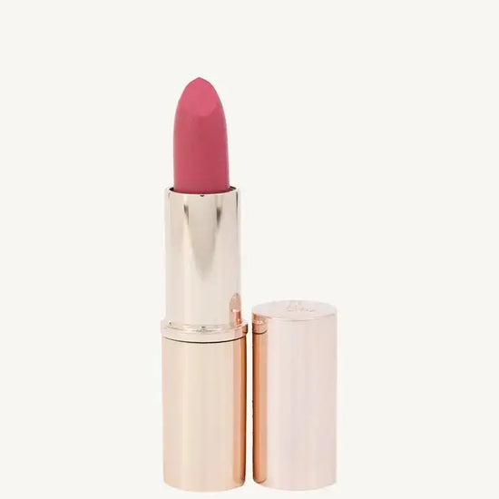 A photo of Pure Anada's Esteem Lipstick in a rose gold tube with a pinkish rose color on a tan background.