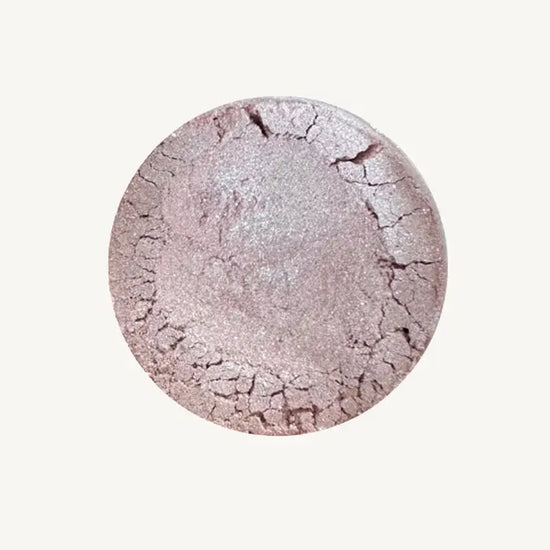 Pure Anada's Velvet Eye Shadow in a light purple / lilac color with a shimmery finish in a round container on a tan background.