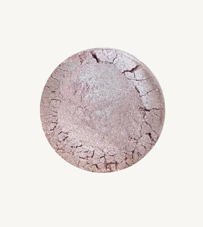 Pure Anada's Velvet Eye Shadow in a light purple / lilac color with a shimmery finish in a round container on a tan background.