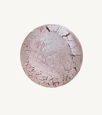 Pure Anada's Velvet Eye Shadow in a light purple / lilac color with a shimmery finish in a round container on a tan background.