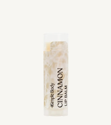 An oval lip balm tube with a label that reads 'Cinnamon Lip Balm'. The packaging is clear, revealing the off-white product inside.