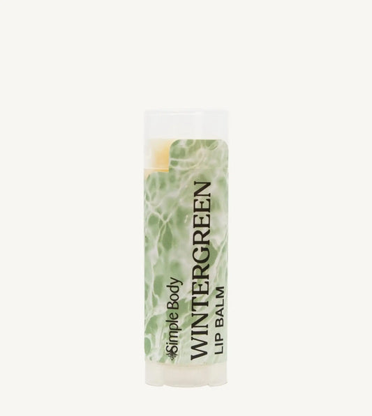 An oval tube of Simple Body Wintergreen Lip Balm with a green and white label, indicating it is nourishing lip care with a minty scent.