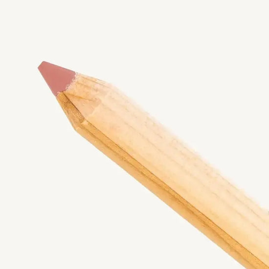 A closeup photo of Pure Anada's lip pencil stick with a warm pink flesh colored tip on a tan background.
