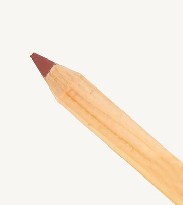 A close up photo of Pure Anada's Lip Pencil in a warm brick red color on a tan background. 