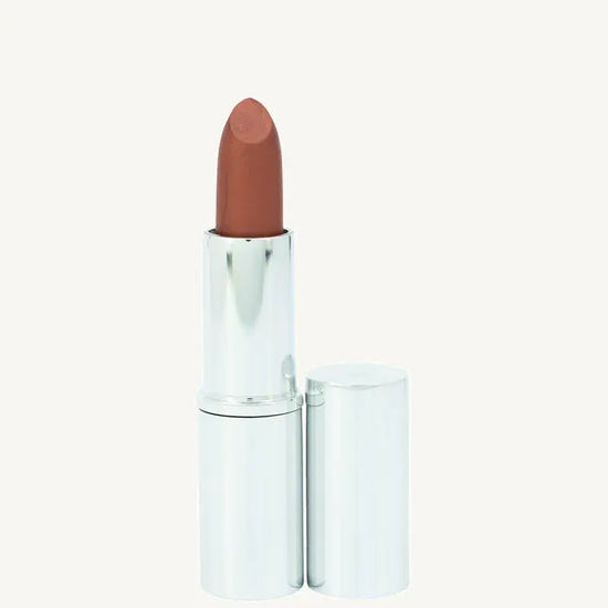 A photo of Pure Anada's Lip Stick in Autumn in a metallic silver tube with a deep orange rust color on a tan backround.