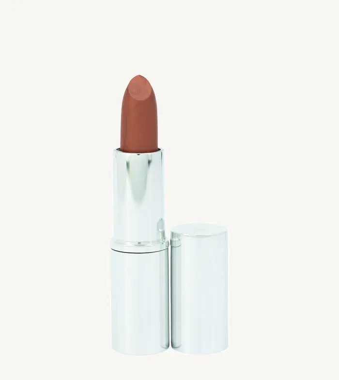 A photo of Pure Anada's Lip Stick in Autumn in a metallic silver tube with a deep orange rust color on a tan backround.