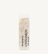 An oval lip balm tube with a label that reads 'Cinnamon Lip Balm'. The packaging is clear, revealing the off-white product inside.