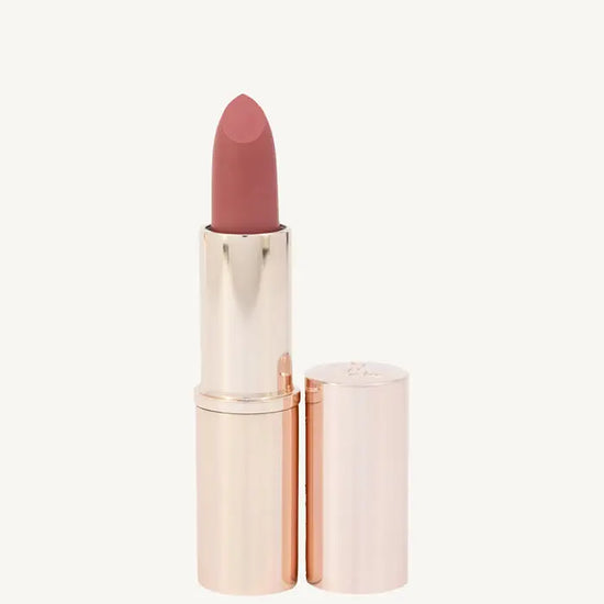 A photo of Pure Anada's Lip Stick in a rose gold tube with a pin / rose color on a tan background.