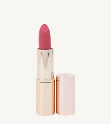 A photo of Pure Anada's Esteem Lipstick in a rose gold tube with a pinkish rose color on a tan background.