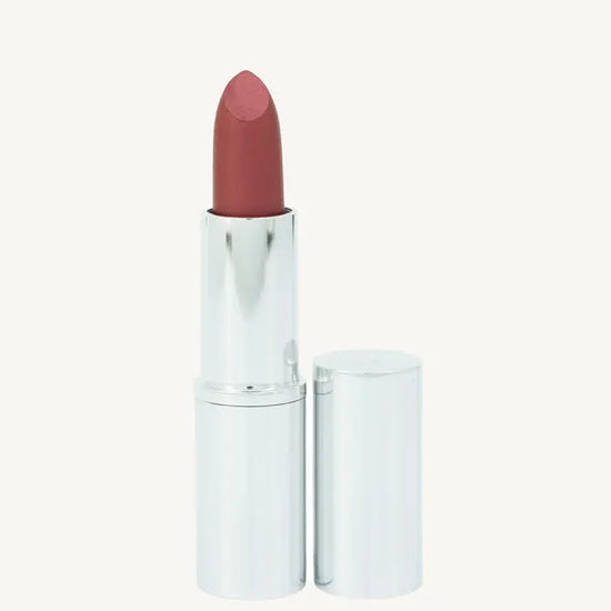 A photo of Pure Anada's Lipstick in Ruby in a silver metallic tube with a deep red slightly shimmery color on a tan background.