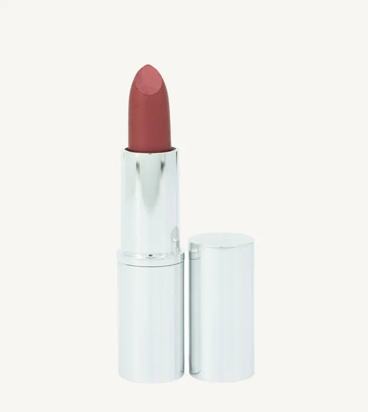 A photo of Pure Anada's Lipstick in Ruby in a silver metallic tube with a deep red slightly shimmery color on a tan background.
