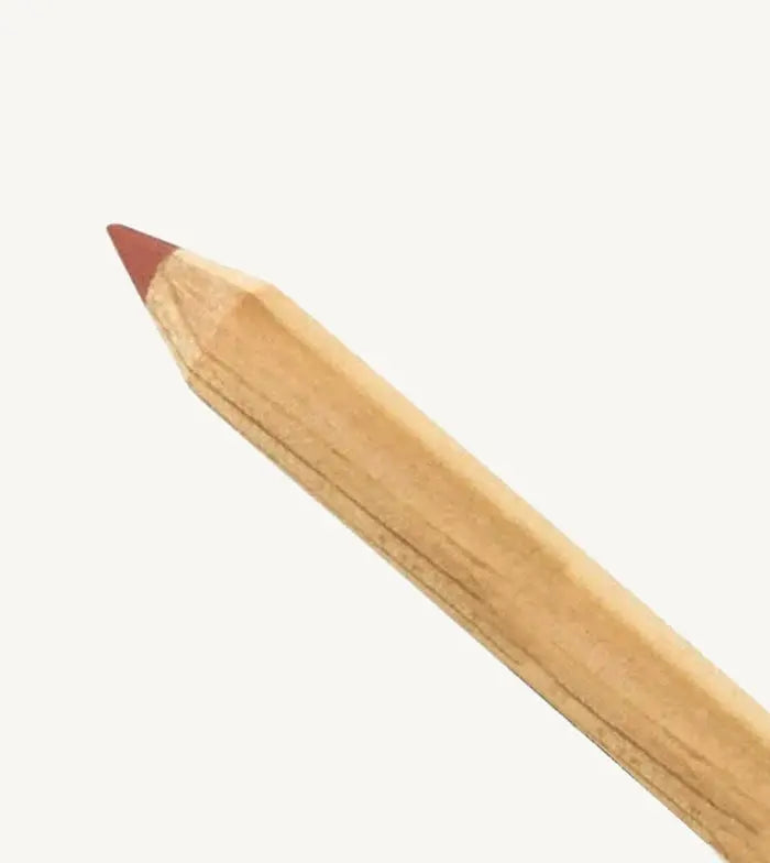 A photo of Pure Anada's Lip Pencil in a natural wood color and the tip is a warm rust color on a tan background.
