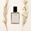 Perfume bottle labeled 'No. 74' with dried flowers on a light background
